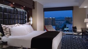 Una habitación de hotel con una cama grande, vistas a la ciudad y un escritorio con una silla.