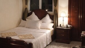 Une chambre à coucher avec un lit en bois, une table de chevet avec une lampe, une armoire et un tapis à motifs.