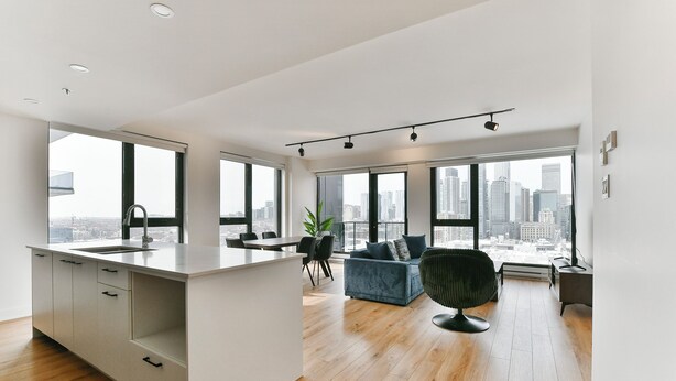 Um apartamento moderno com cozinha, área de refeições e sala de estar, com grandes janelas e vista para a cidade.