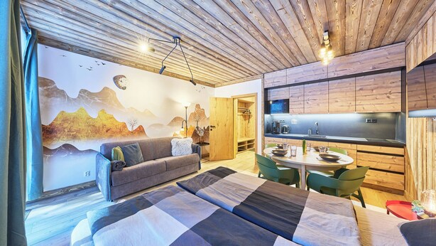 Ein modernes Schlafzimmer mit einem großen Bett, einer Couch, einem Esstisch und einer Küchenzeile.
