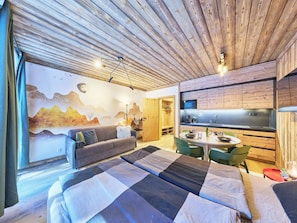 Ein modernes Schlafzimmer mit einem großen Bett, einer Couch, einem Esstisch und einer Küchenzeile.