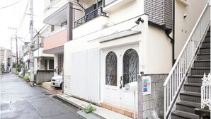 A residential street with houses, a white door with decorative ironwork, a mailbox, and a staircase. - Honmachi 5-chome (Tokyo)
