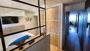 Ein modernes Hotelzimmer mit einem großen Spiegel, Holzboden und Blick auf den Flur.