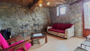 A rustic room with stone walls, wooden beams, a red sofa, and a small table. - Vacation home Ester by Interhome (Castel di Casio)