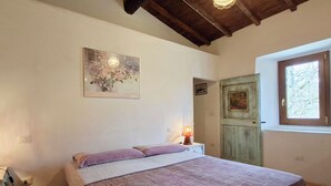 A bedroom with a bed, a lamp, a painting, a door, and a window. - Vacation home Ester by Interhome (Castel di Casio)