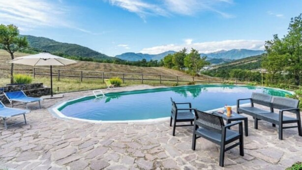 A pool area with stone flooring, lounge chairs, and a table with chairs. - Vacation home Ester by Interhome (Castel di Casio)