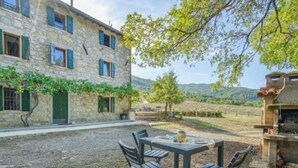 A stone building with a patio table and chairs, surrounded by a vineyard and hills. - Vacation home Ester by Interhome (Castel di Casio)