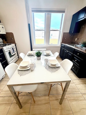 Una cocina con una mesa de comedor para cuatro personas, estufa, armarios y ventana con vistas.