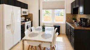 Eine moderne Küche mit Essbereich, ausgestattet mit Kühlschrank, Herd, Mikrowelle und einem Esstisch mit Stühlen.