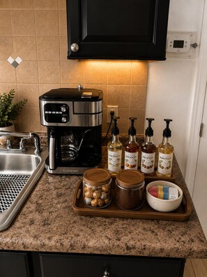 A kitchen with a coffee maker, jars of condiments, and a tray with snacks. - Boutique 2BR ,20 Min NYC, Sleeps 6, Coffee Bar, Nintendo + Family Extras (West New York)