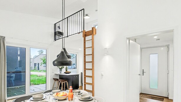 Et moderne spiseområde med et rundt bord, stole og en hængende pendel.