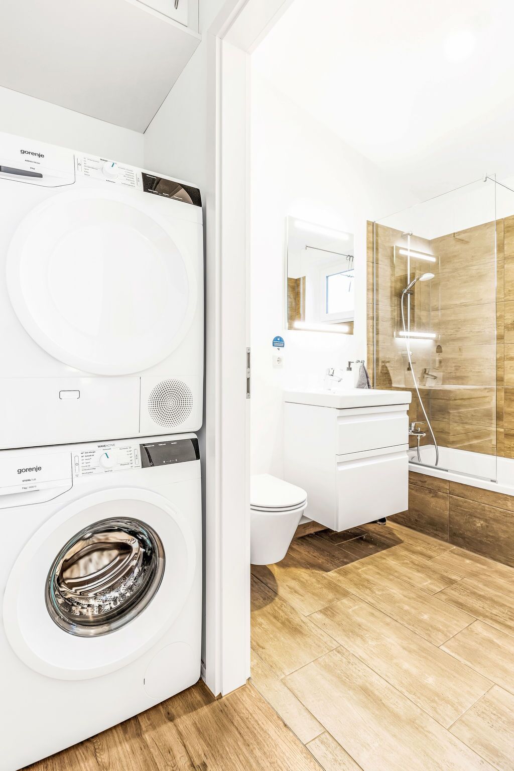 A modern bathroom with a washing machine, a toilet, and a shower area.