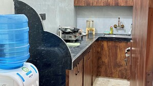 Een keuken met houten kastjes, een gasfornuis, een waterdispenser en een spoelbak.