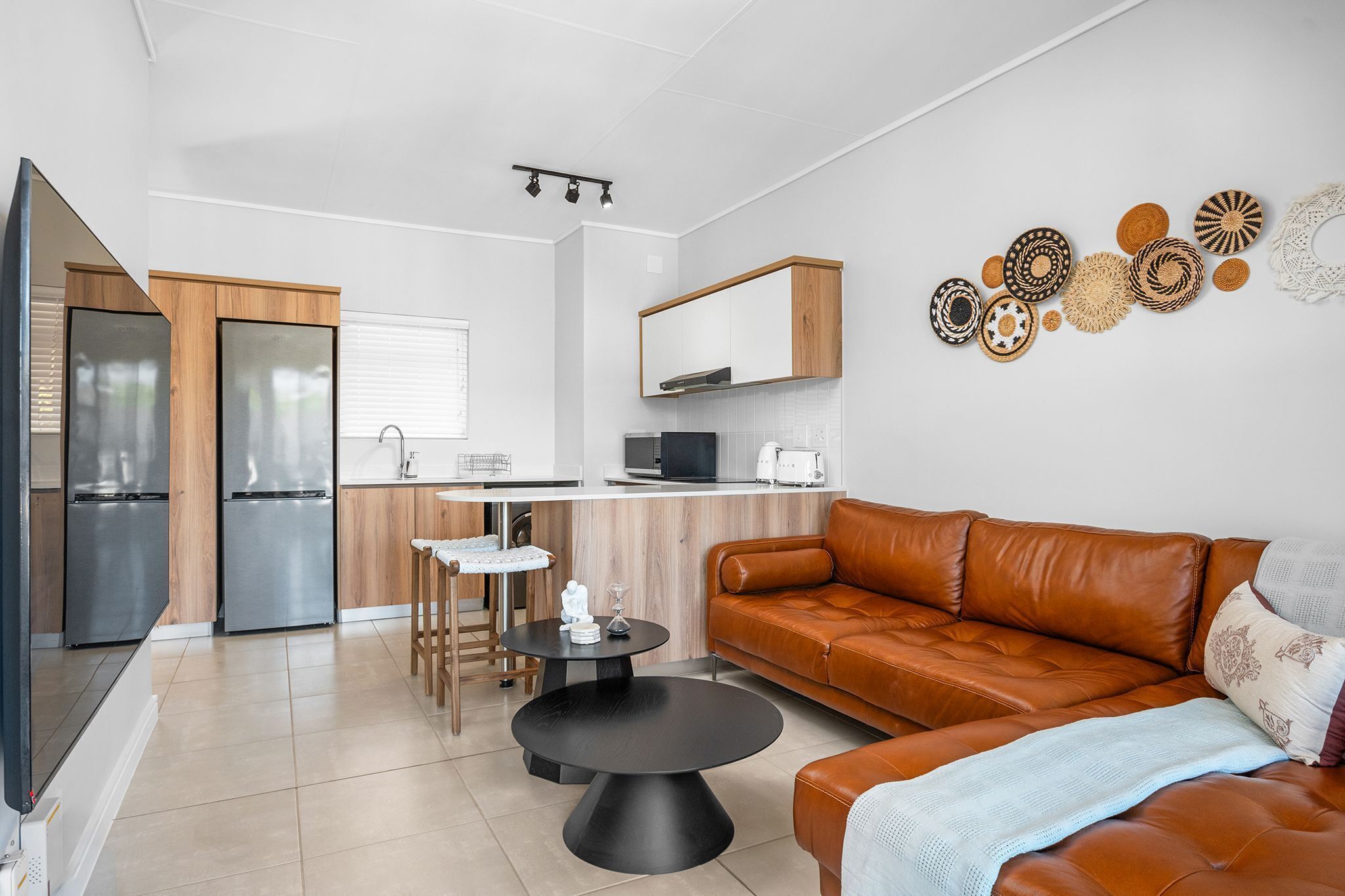 Una cocina moderna con comedor, un sofá de cuero marrón y una pequeña mesa redonda.