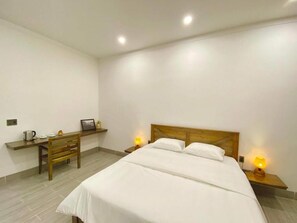A bedroom with a bed, bedside tables, a wooden chair, and a small desk with a lamp. - Hoa Homestay Phu Quoc (Phu Quoc)