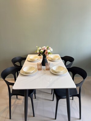 A dining table set with plates, bowls, and a vase of flowers. - Modern Two Bedroom Ipoh City Apartment with Pool, Gym and Free Parking (Ipoh)
