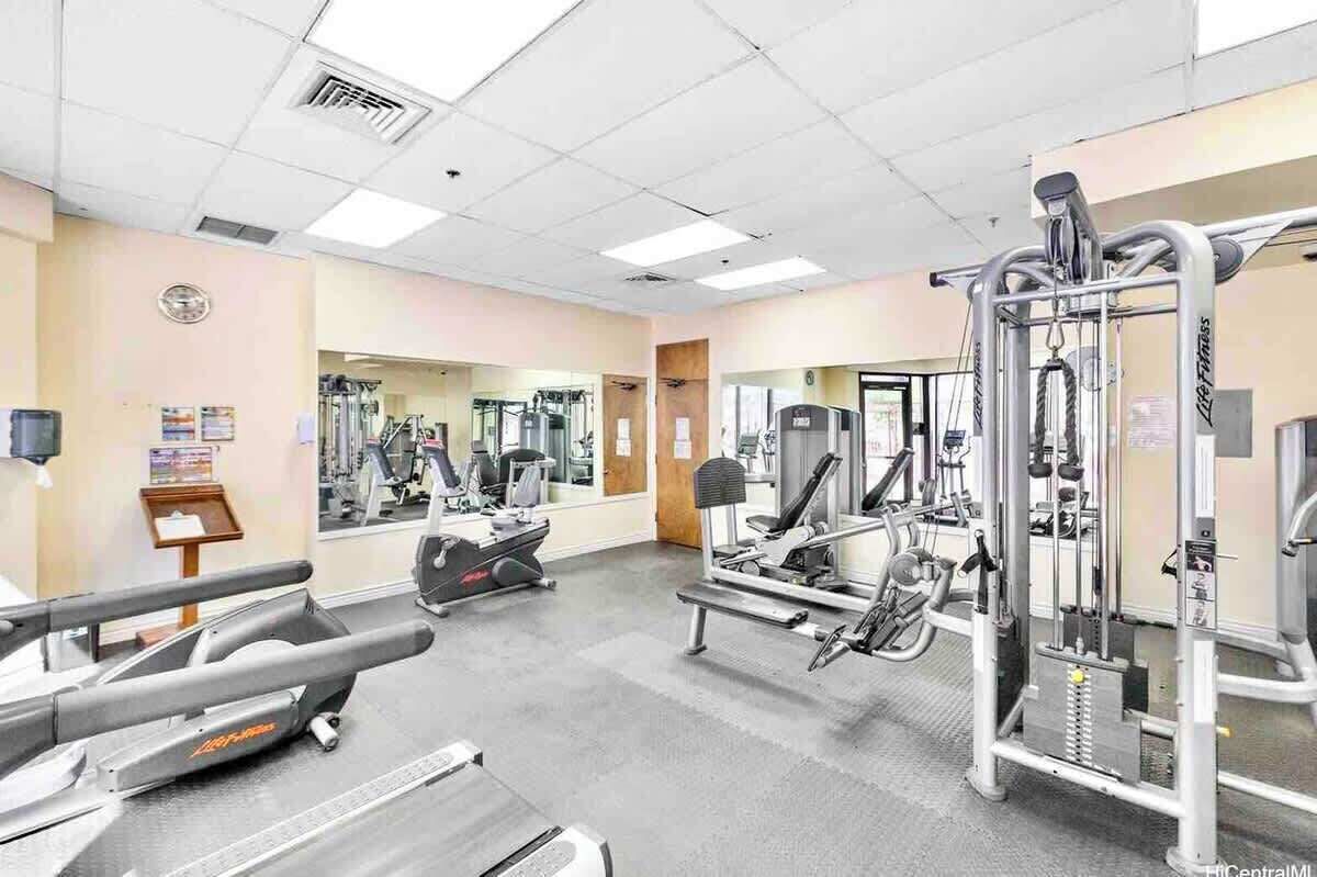 A gym with cardio machines, weight training equipment, and mirrors on the walls.
