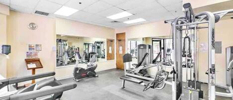 A gym with cardio machines, weight training equipment, and mirrors on the walls.
