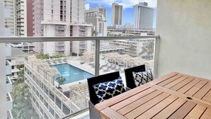 Een balkon met uitzicht op een zwembad en hoge gebouwen.