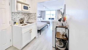 Een moderne hotelkamer met een kitchenette, een bed, een eethoek en uitzicht op de stad.