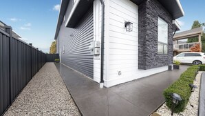 Ein modernes Haus mit Garagentor, Steinaußenwand und Auffahrt mit Kies und einem Fußweg.