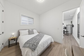A bedroom with a bed, bedside table, and a window. - Surrey Modern Private 1 Bedroom Suite with Kitchen (Surrey)