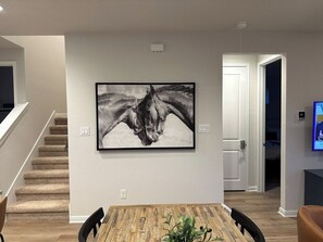 A dining area with a table, chairs, and a framed artwork on the wall. - The Hofstaat Haus: Modern NB Retreat (New Braunfels)