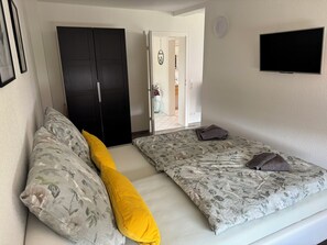 Ein Schlafzimmer mit zwei Betten, einem Kleiderschrank, einem Fernseher und einer Tür zum Badezimmer.