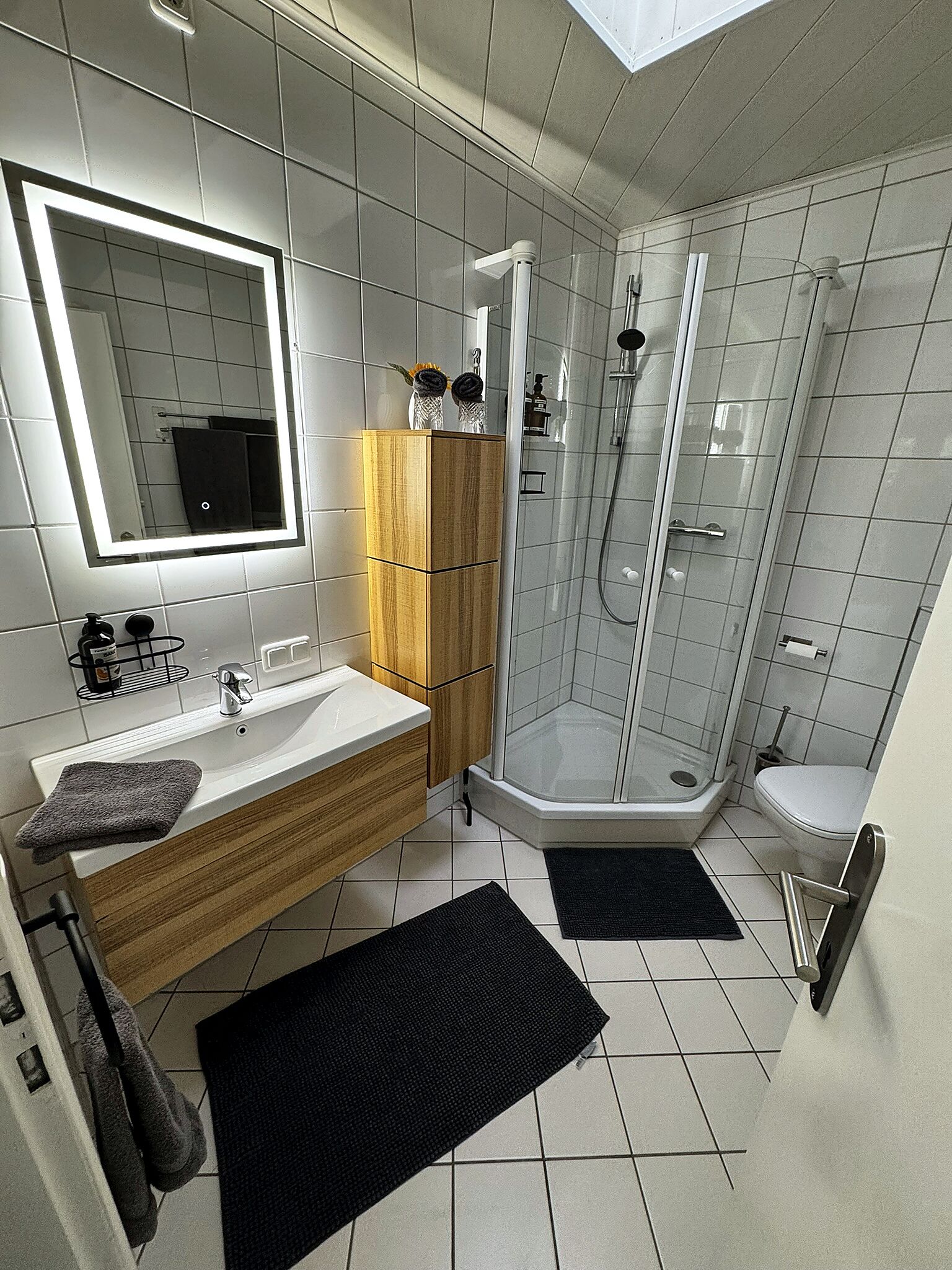 A modern bathroom with a vanity, mirror, shower, and toilet.
