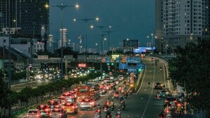 Affollata strada cittadina di notte, con diverse corsie di traffico, auto e motociclette.