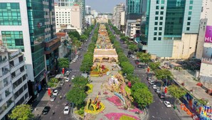 Una strada cittadina con edifici moderni, una rotonda centrale e un'ampia fiorita.