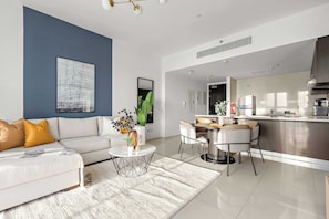 A modern living room with a sofa, coffee table, and dining area. - Silkhaus Chic 1bdr Horizon Tower Al Reem (Abu Dhabi)