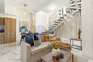 Ein modernes Wohnzimmer mit Sofa, Couchtisch und einer Treppe.