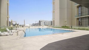 Una piscina con lettini e vista sugli edifici circostanti.
