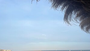 A beach with white umbrellas and lounge chairs, a clear sky, and a sandy shore. - 2 p+balcony ideally located with splendid view of the Canal Royal and the port of Sète (Sète)