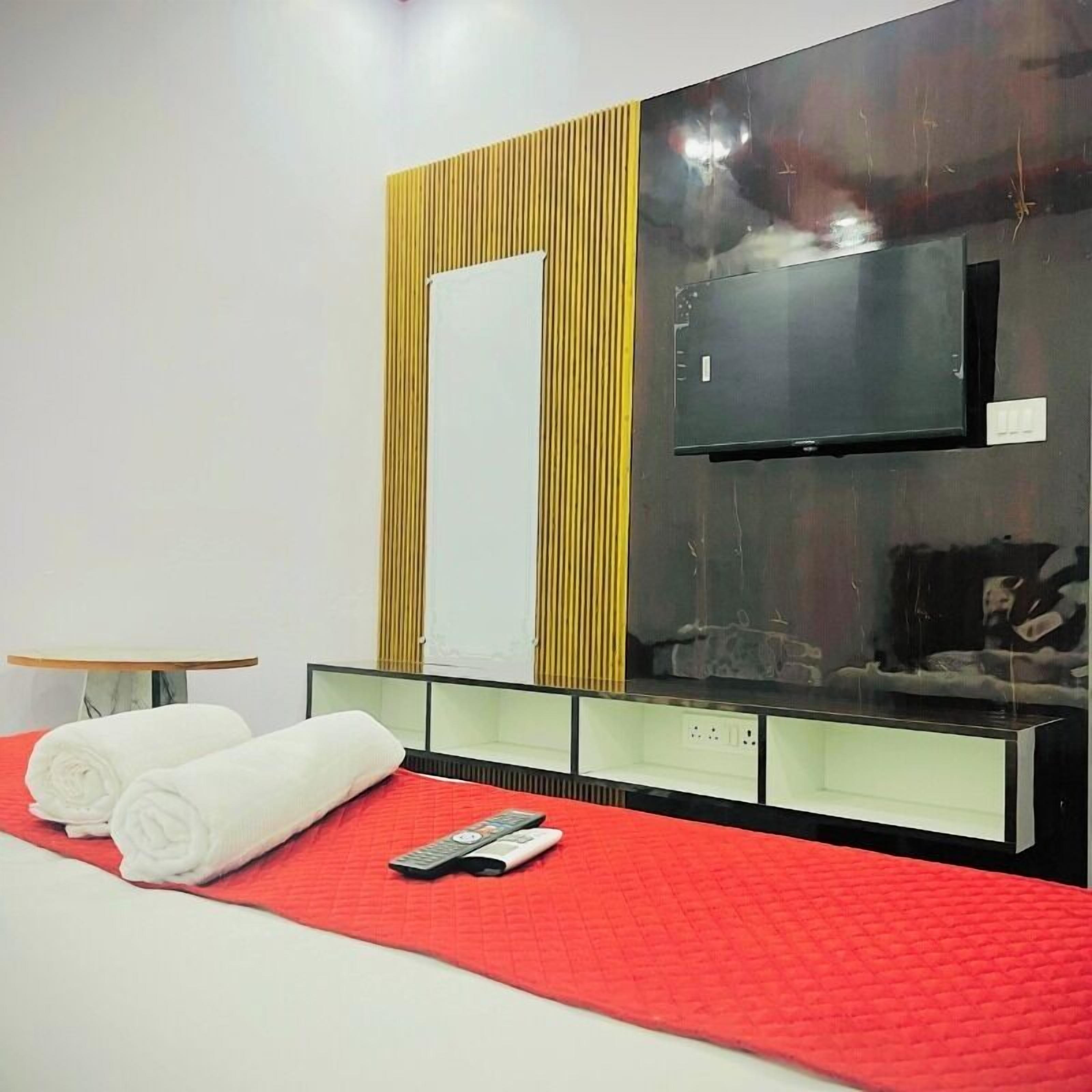 A hotel room with a bed, a TV, and a mirror.