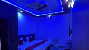 A modern hotel room with a bed, a ceiling fan, an air conditioning unit, and a small table. - Sky Hotel (Lucknow)