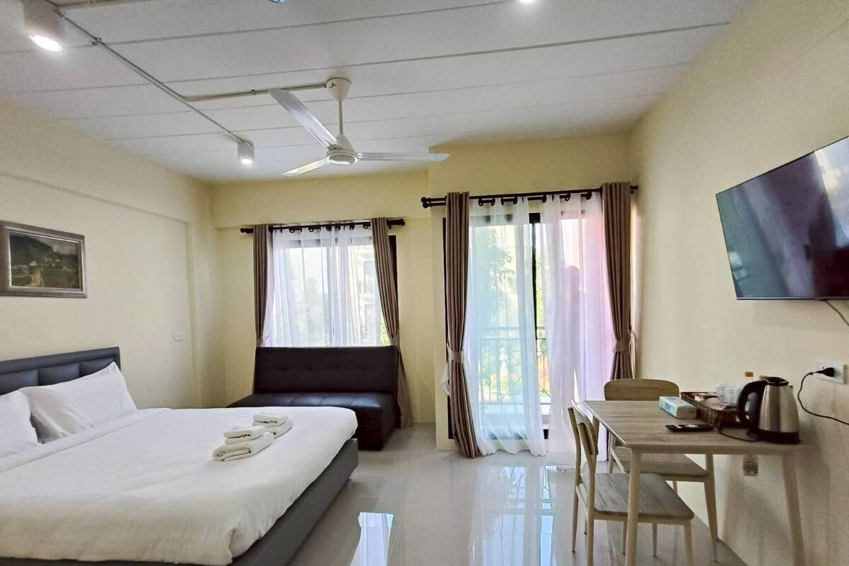 A hotel room with a bed, a desk, a chair, a television, and a window with curtains.