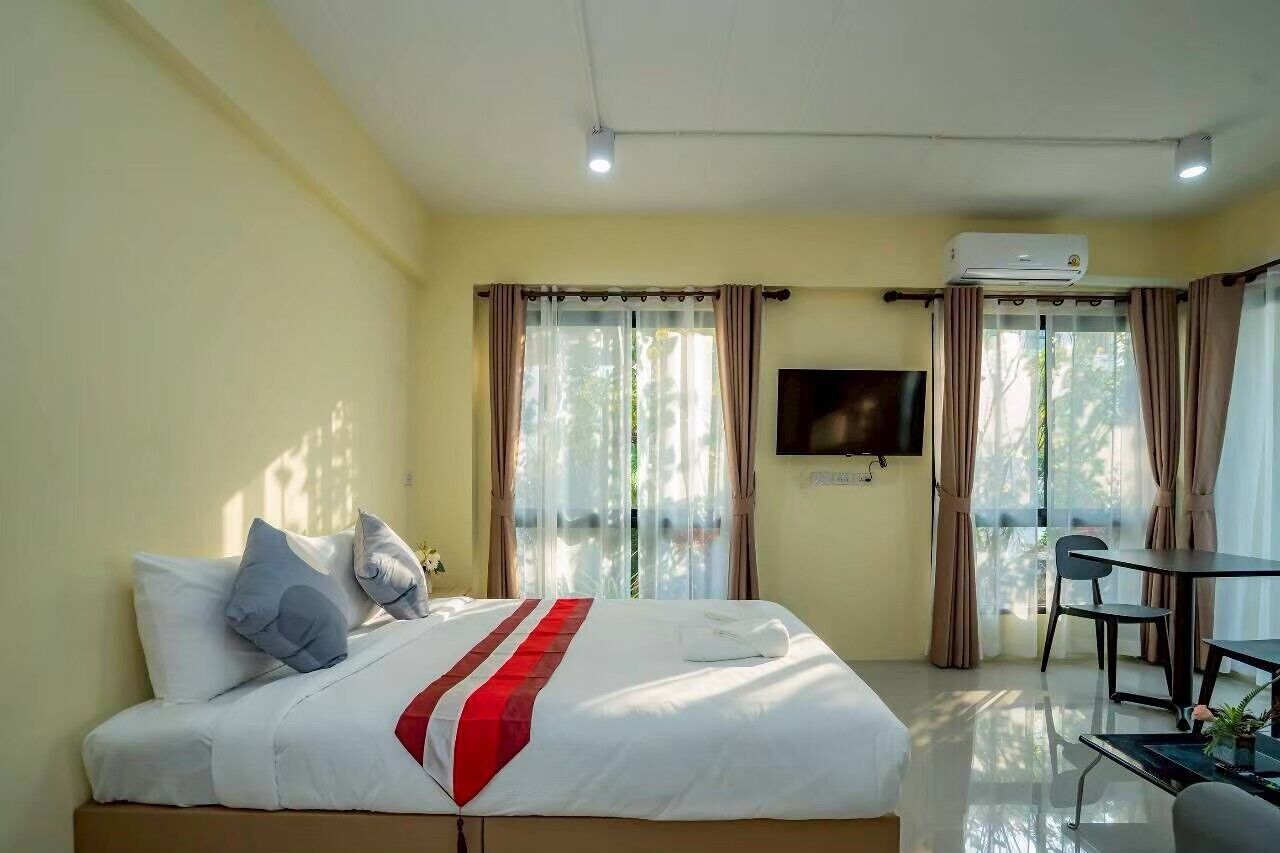 A hotel room with a bed, a TV, a desk, and a chair.