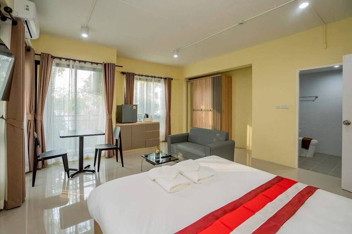 A hotel room with a bed, a desk, a chair, a sofa, and a television.