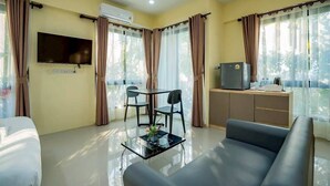 Een hotelkamer met een bed, een televisie, een eettafel met stoelen, een bank en een kitchenette.