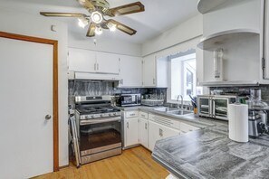 A modern kitchen with white cabinets, a stainless steel stove, a microwave, and a toaster.