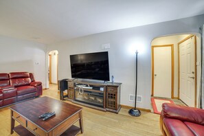 A living room with a flat-screen TV, leather sofas, a coffee table, and a floor lamp.