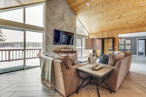 Ein geräumiges Wohnzimmer mit großem Fenster, Kamin und Wand-Fernseher.