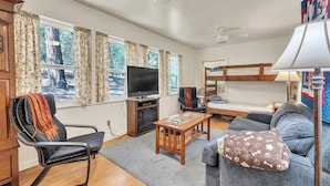 A cozy living room with a television, a sofa, a chair, a bunk bed, and a lamp. - Lakefront Cabin w/ Dock, Kayaks & Full Kitchen (Nevada City)