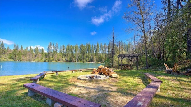 A lakeside campsite with picnic tables, a fire pit, and a wooden structure. - Lakefront Cabin w/ Dock, Kayaks & Full Kitchen (Nevada City)