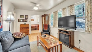 A living room with a sofa, a coffee table, a TV, and a fireplace. - Lakefront Cabin w/ Dock, Kayaks & Full Kitchen (Nevada City)