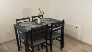 En matplats med ett svart bord och stolar, en vit vas med blommor och en mönstrad bordslöpare.