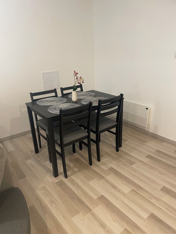 A dining area with a black table and chairs, a white vase with flowers, and a patterned table runner.