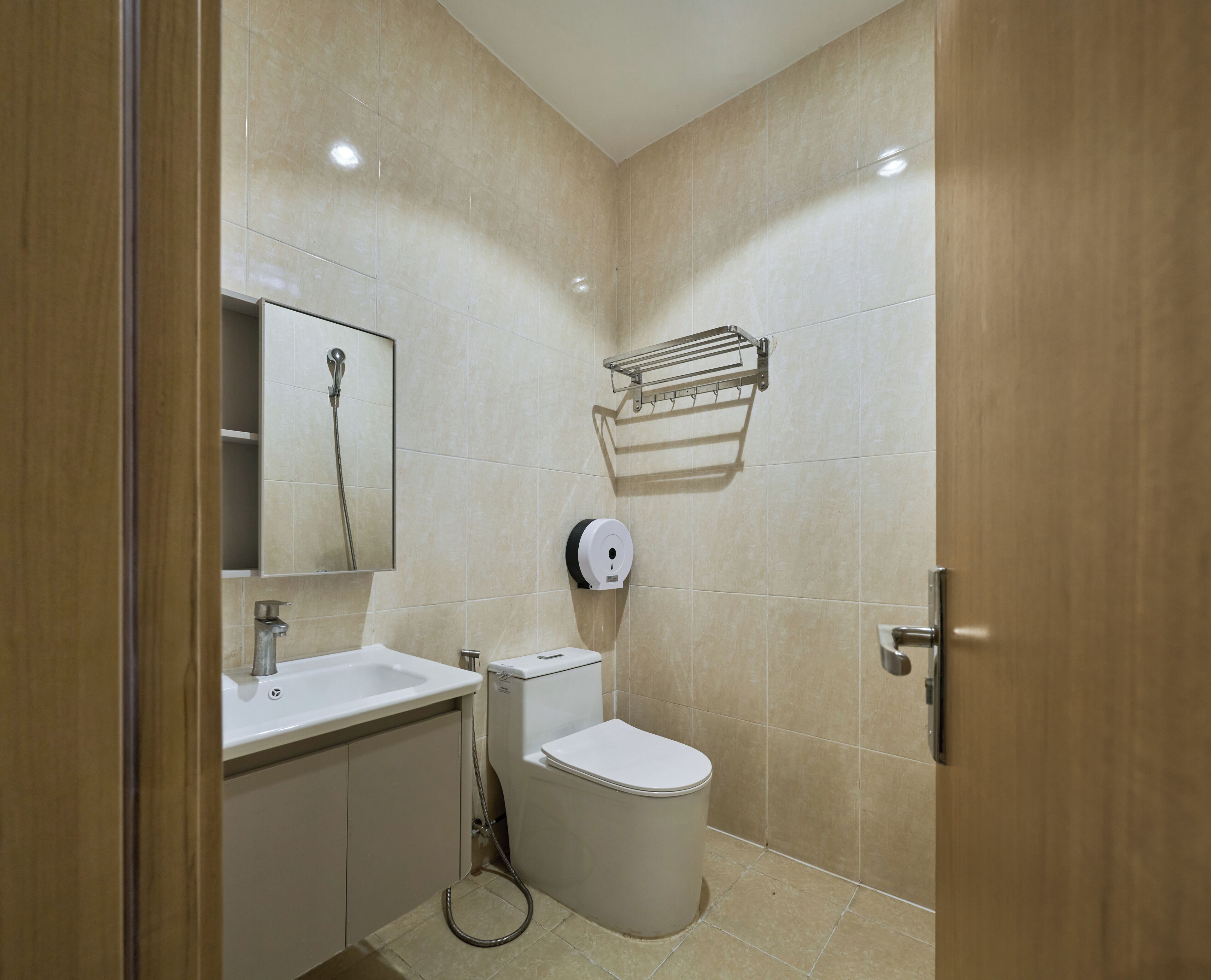 Un baño con inodoro, lavamanos, espejo, toallero y secador de manos.